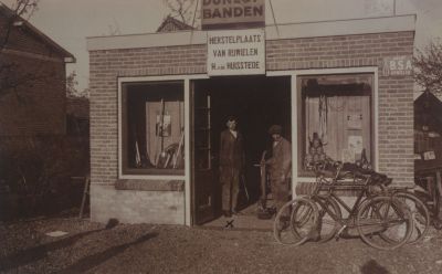 Rijwielherstelplaats-H-van-Huisstede
Rijwielherstelplaats H. van Huisstede.
In de deuropening links de eigenaar Manus van Huisstede en rechts W. Kalf. 
In 1999 is de rijwielherstelplaats gesloopt en is op die plaats de snackbar Kwalitaria gevestigd.
