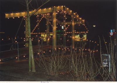 Versierde-Brug
Op de plaats van de vroegere brug is door de middenstand tgv de feestmaand een replica van de oude Brug voorzien van lampjes geconstrueerd Op de achtergrond is de lichtreclame van dames heren-modezaak en woninginrichting Brinkers te zien .
Tussen 