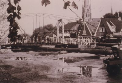 Demping-van-de-Reevaart
Dempen van de Reevaart.
OP deze foto staat de Brug over de Reevaart nog.
Op de achtergrond de Dammerweg en de toren van de R.K Kerk
