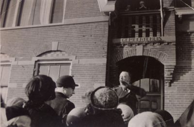 Dameskoor-voor-het-Gemeentehuis
Chris Hageman met het dameskoor voor het Gemeentehuis.
Let op de 2 mensen boven de ingang op het balkon.
Zij luisteren stilletjes mee.
