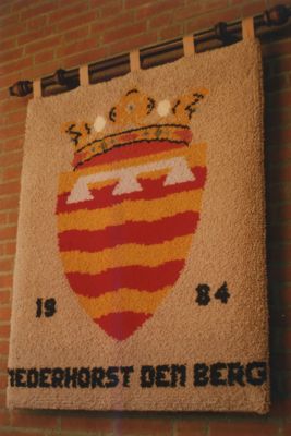 Wandkleed-wapen-Nederhorst-den-Berg
Dit wandkleed is geschonken in 1984 door de afd. Burgerlijke stand en de bevolking bij de opening van het verbouwde gemeentehuis. 
Getekend door P. Lokkart en geknoopt door Willy van Deutekom.
