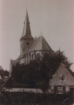 Protestantse-kerk-Willibrord
Gezicht op de prot kerk Willibrordkerk gezien vanaf de Kerkstraat .
De woning links is een zg diaconiehuisje bestemd voor de armlastigen van de kerkelijke gemeente.
De woning was in tweeen gedeeld.
Na renovatie  wordt het huis nu (2007) bewoond door mw Kostelijk. 
Achter de lange witte muur van betonplaten was een fietsenstalling voor gebruik door de kerkgangers. 
Ook was er een regenwatertappunt. 
Na verwijdering van die muur is het pleintje gerenoveerd en thans (2007)  staat daar het zg. Verzetsmonument”.
Trefwoorden: Regenwatertappunt; diaconiewoningen; fietsenstalling.
