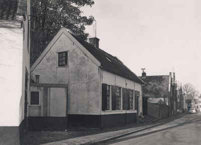 Kosterswoning
Kosterswoning met links de toegangsdeur van meubelmakerij-van Huisstede. 
Rechts naast de kosterswoning de stenen trap-met-hek naar de boven gelegen NH-Willibrordkerk.
Achter de houten schutting was de fietsenstalling van de kerk.
De stalling werd gesloopt toen de muur onder de kerk is gerestaureerd (1960/70).
Op het toen ontstane pleintje is in 1995 het Verzetsmonument geplaatst.
Trefwoorden: Nederlands Hervormd, Willibrordkerk