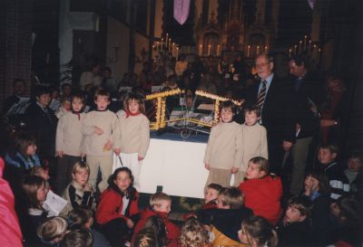 Kerstviering-op-het-Plein
Aanbieding De Brug een Eeuwwijzer op 17 dec. 1999. 
Kerstviering op het Plein  i.v.m. het weer werd dit in de kerk gedaan. 
V.l.n.r. (in het wit) de Bergse Vijfling. Burgemeester J. Goudberg, Cees Stalenhoef en Willy Das.
