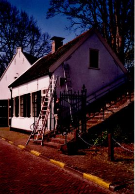 Toegang-tot-Willibrordkerk
De trap naar de kerk Daarnaast de woning waar de koster Han van Asselt heeft gewoond.
De lamp wordt op een houten schild geplaatst.
Er kwamen roeststrepen op de muur door deze lamp.
