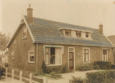 Behang-en-verfartikelenwinkel-Fam-R-Baar
Woonhuis van de familie Baar voor de verbouwing.
Voordeur en het kleine raam rechts op de foto worden dan winkel. 
Het was een winkel in behang en verfartikelen.
De winkel wordt gesloten in 1992.
