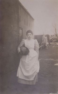 Wasvrouw
Aletta van Wijngaarden.
Het gebouw links is de werkplaats van timmerman Verkaik. 
Op  het rek op de achtergrond hangt wasgoed te drogen.
Nu (2007) woont hier o.a. de familie Overes.
Trefwoorden: Werkplaats; timmerman; wasrek