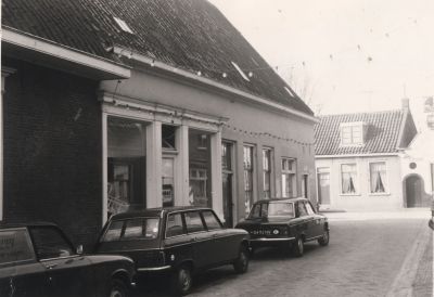 Hoek-Brug-en-Kerkstraat
Magazijn van de kruidenierszaak Snel, thans  2007,  kapsalon la Papilotte.
Rechts op de foto nog juist het uithangbord van kruidenierszaak 4=6 , eigendom van de fam Schoordijk.
Links de oude situatie in de Brugstraat met de kruidenierswinkel van Snel. Op de achtergrond de Kerkstraat. Het huis met de poort was ooit een school
Trefwoorden: kruidenier school