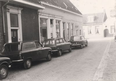 Magazijn-van-Fam-Schoordijk
Magazijn van de kruidenierszaak Schoordijk.
Links op de foto nog juist het uithangbord van kruidenierszaak 4=6 eigendom van de fam Schoordijk.
Het woonhuis, uiterst links, werd bewoond door de fam. Bornheim.
Uiterst rechts : “droge wasbaas Edelweis”, eigendom van  de heer Gerard Snel
