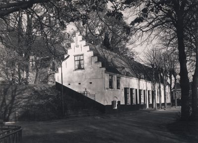 Tegen-Den-Berg-aangebouwde-woning
Links voert de trap naar de toren van de Willibrordkerk.
Uiterst rechts (voorheen timmer-werkplaats van Van Huisstede) in gebruik als kantoorruimte. 
In het midden, achter de tweede boom links is de toegang (voor gehandicapten) per lift tot de kerk.
