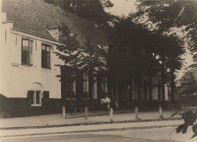 Woning-meubelmaker-C-van-Huisstede
De woning is gelegen aan het pleintje Torenweg/JB-plein/Kerkstraat. 
Achter de deur naast het bankje is  in de jaren 1980/1990 een lift aangebracht  voor kerkgangers voor wie de
trappen naar de kerk een bezwaar zijn.
Op het bankje zitten: Meubelmaker C.van Huisstede met zijn echtgenote. In het midden de heer C.van Vuren.
